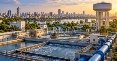 Municipal water treatment tanks and pipes near a water tower and city skyline