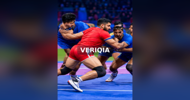 Kabaddi defenders grappling with a raider on a blue indoor court